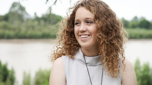 Close up of a girl with red curly hair smiling - Australian Stock Image