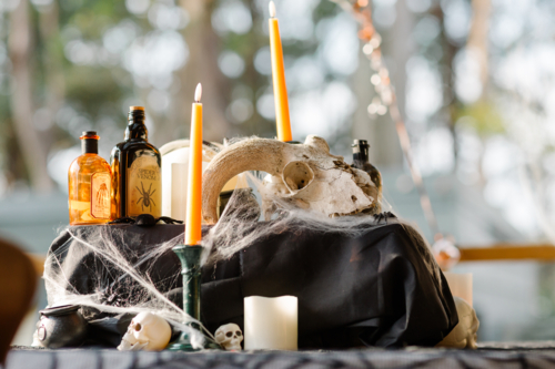 Close-up of a Halloween-themed tabletop arrangement with amber, dark glass bottles and eerie props - Australian Stock Image