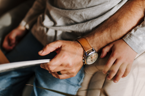 Close up of a man holding a book with son sitting on his lap. - Australian Stock Image
