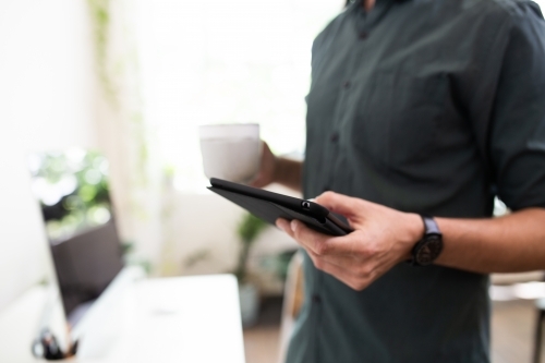 Close-up of a man's hands using an e-device - Australian Stock Image