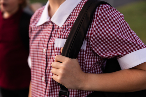 close up of a school student holding a bag strap over a shoulder - Australian Stock Image