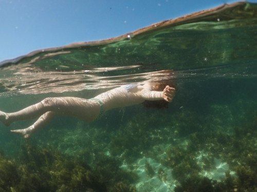 Close up of a teenage girl floating in an ocean rock pool - Australian Stock Image