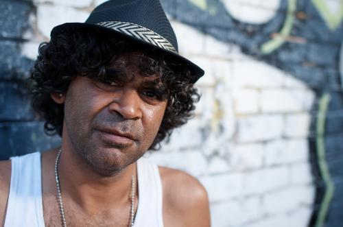 Close Up of a Young Aboriginal Man against a Brick Background - Australian Stock Image