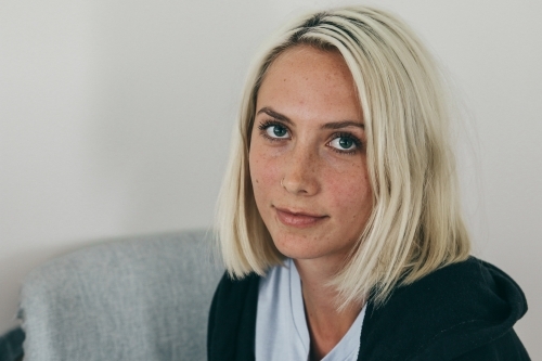Close up of a young blonde woman looking up from a chair - Australian Stock Image