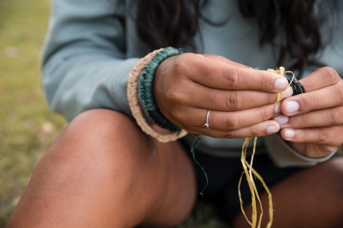 Close up of an Aboriginal girl, weaving threads to make bangles and bracelets - Australian Stock Image