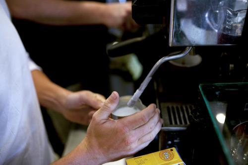 Close up of barista steaming milk - Australian Stock Image