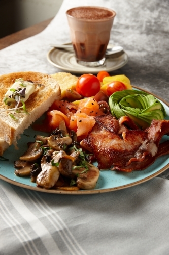 Close up of big breakfast dish with hot chocolate on table - Australian Stock Image