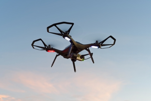 Close-up of black drone, UAV, RPAs flying in a park at sunset - Australian Stock Image