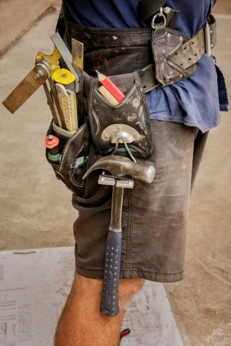 Close-up of builder wearing shorts and tool belt on construction site