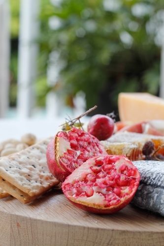 Close up of cheese board with cheese, crackers and pomegranates