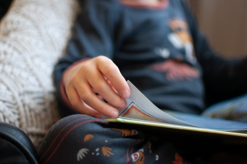 Close up of child's hand turning page of book