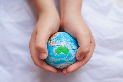 Close up of child's hands holding world globe with Australia map - Australian Stock Image