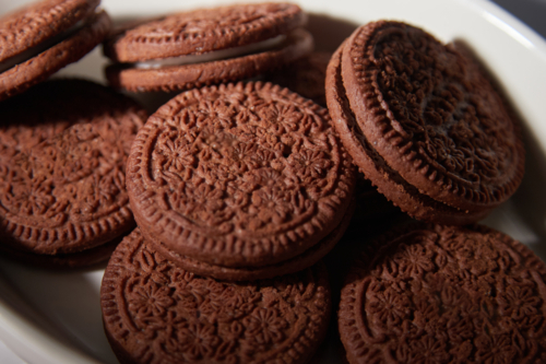 close up of chocolate cream biscuits on white plate - Australian Stock Image