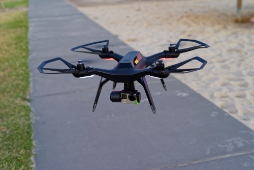 Close up of drone with camera attached flying in an empty park UAV, RPAS - Australian Stock Image