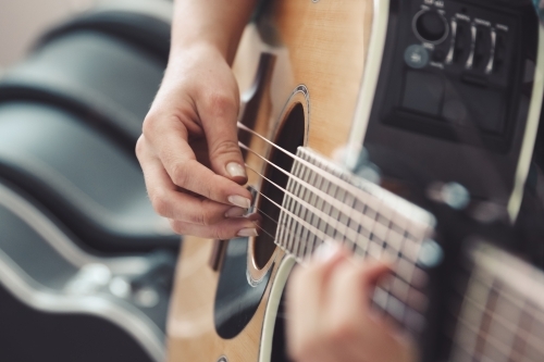 Close up of female hands playing an acoustic guitar - Australian Stock Image