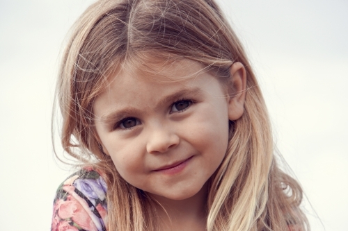 Close up of five year old girl with blonde hair smiling - Australian Stock Image