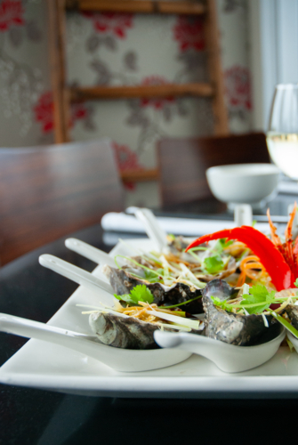 Close up of fresh oysters on spoons with garnish in a restaurant - Australian Stock Image