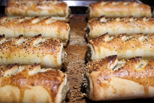 Close up of freshly baked sausage rolls lined up on a baking tray
