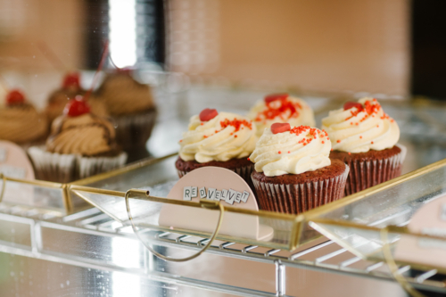 Close-up of freshly made red velvet cupcakes showcased in a glass bakery display - Australian Stock Image