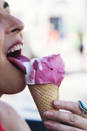 Close up of girl licking an ice cream cone - Australian Stock Image