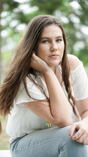 Close up of girl with long hair sitting outdoors - Australian Stock Image
