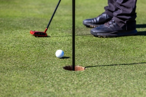 Close-up of golf ball on course near hole - Australian Stock Image