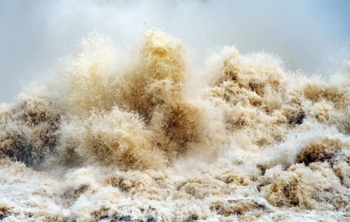 Close up of gushing water spraying out from over full dam. - Australian Stock Image