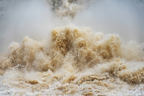 Close up of gushing water spraying out from over full dam. - Australian Stock Image