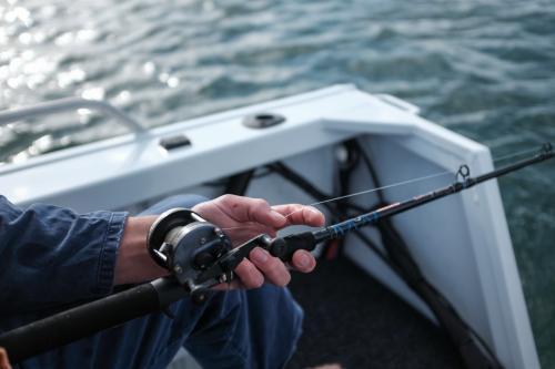 close up of hand and fishing reel while fishing - Australian Stock Image