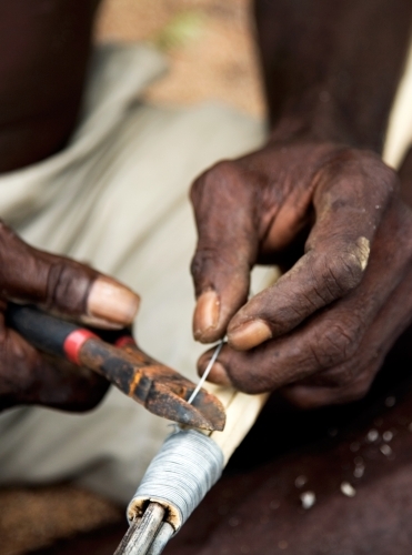 Close up of indigenous persons hands working with tools - Australian Stock Image