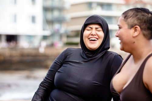 Close up of Italian-Filipino woman having a conversation with French Islander woman in tidal pool - Australian Stock Image