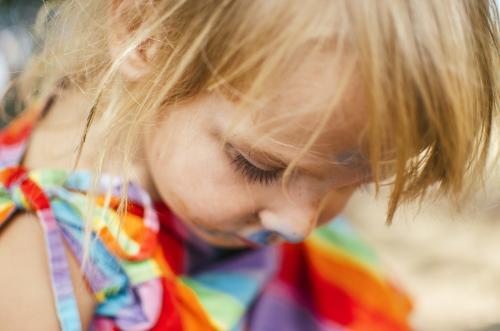 Close up of little girl in a rainbow dress - Australian Stock Image