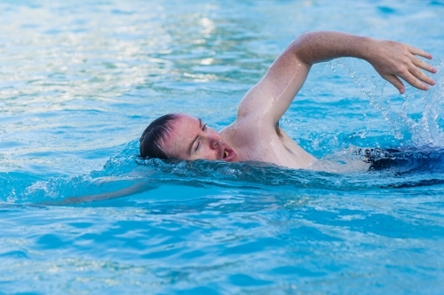 Close up of man swimming laps of pool