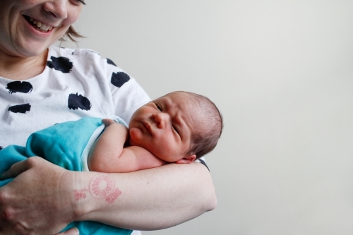 Close up of mother holding her newborn baby and smiling - Australian Stock Image
