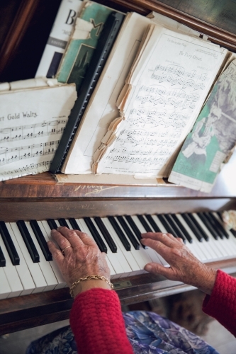 Close-up of old lady's hands playing the piano with sheet music