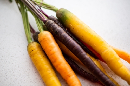 close up of rainbow purple, yellow and orange carrots