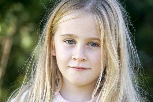 Close-up of Six year old girl with blonde hair looking serious - Australian Stock Image