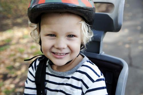 Close up of smiling boy wearing helmet in bike seat