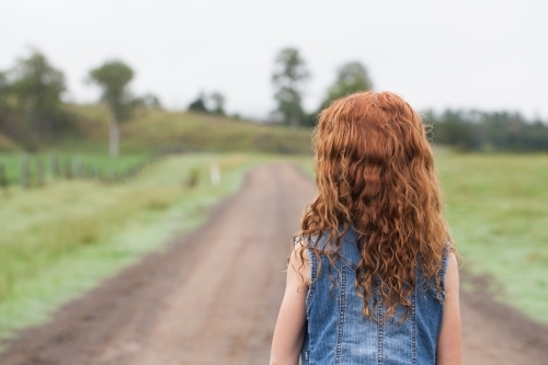 Close up of the back of a young girl on a dirt road