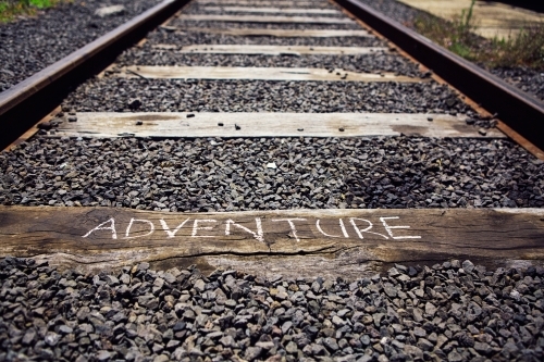 Close up of train track with the word Adventure written on a sleeper - Australian Stock Image