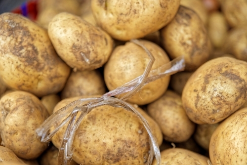 Close-up of unwashed brown potatoes for sale at fresh produce stall at market - Australian Stock Image