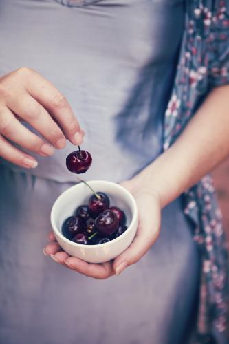 Close up of woman holding a bowl of cherries