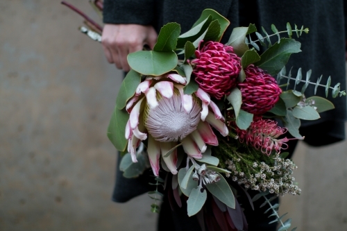 Close up of woman's hand holding a bouquet of native flowers - Australian Stock Image