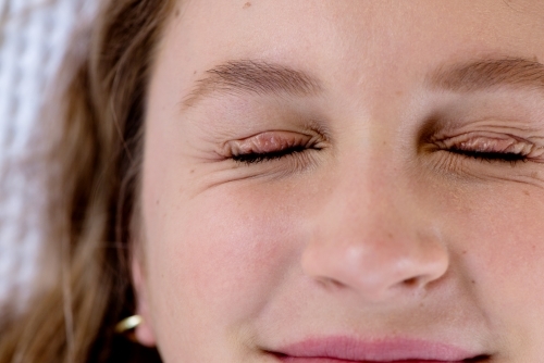 close up of woman with eyes squeezed shut - Australian Stock Image