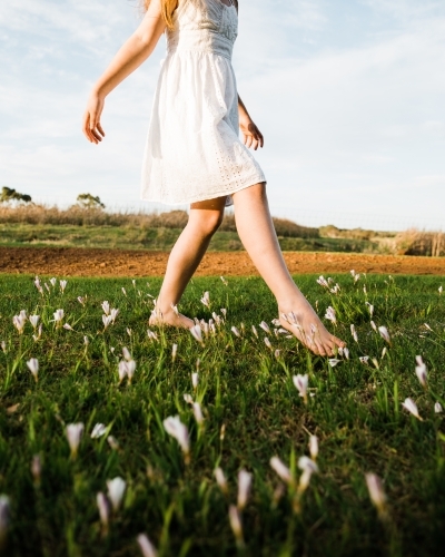 Close up of young girls legs walking in a field of flowers