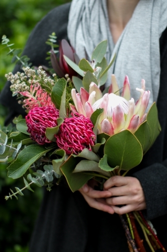 Close up of young woman holding a bouquet of native flowers - Australian Stock Image