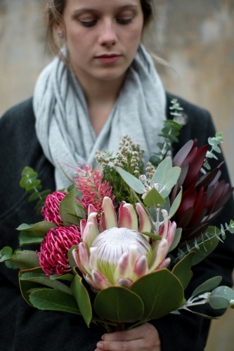 Close up of young woman holding a bouquet of native flowers - Australian Stock Image