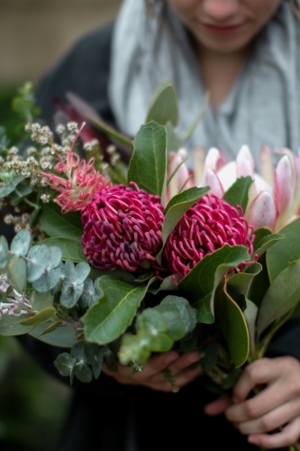 Close up of young woman holding a bouquet of native flowers - Australian Stock Image