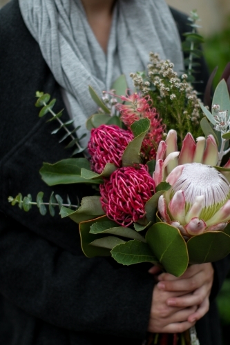 Close up of young woman holding a bouquet of native flowers - Australian Stock Image