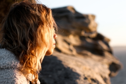 Close up partial portrait of young woman on clifftop at sunrise
